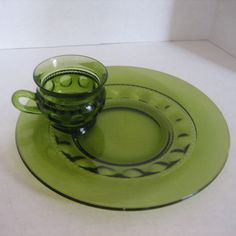 a green glass cup and saucer sitting on top of a plate