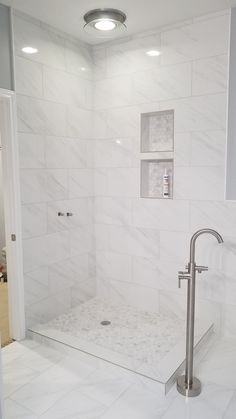 a bathroom with white marble walls and flooring, including a walk in shower area