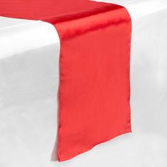 an orange and white table runner is on top of a white table with a red napkin