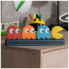 a group of pac - man toys sitting on top of a wooden table next to a clock