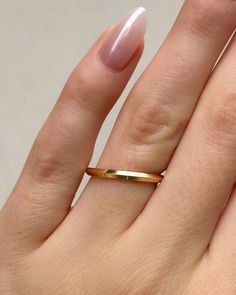 a woman's hand with a gold ring on top of her finger and nails