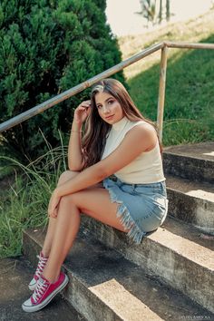 a young woman sitting on the steps with her legs crossed and looking at the camera