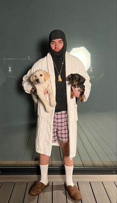 a man holding two puppies in his arms while standing next to a glass wall