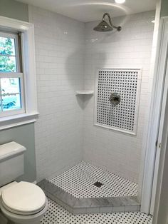 a white toilet sitting next to a shower in a bathroom with black and white tiles