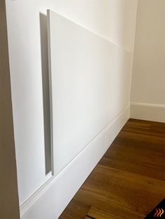 an empty room with white walls and wood floors