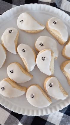 a white plate topped with cookies covered in frosting and ghost faces on top of each other