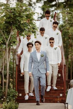 a group of men in suits and sunglasses walking down stairs with one man wearing white