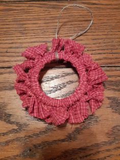 a red and white ornament hanging from a wooden table with string on it