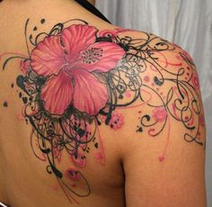 the back of a woman's shoulder with tattoos on it and flowers in the middle