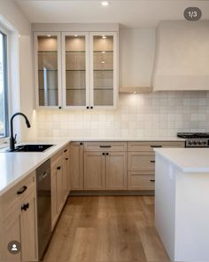 an empty kitchen with white cabinets and wood flooring on the counter top, along with a dishwasher