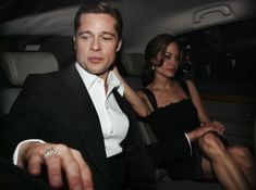 a man and woman sitting in the back seat of a car with their hands together