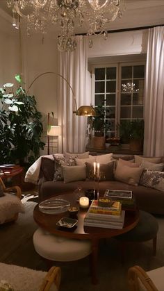 a living room filled with lots of furniture and a chandelier hanging from the ceiling