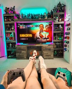 two people sitting in front of a tv with video game remotes on their feet