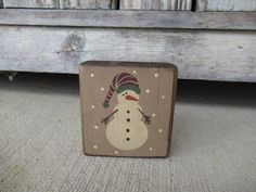 a wooden block with a snowman painted on it