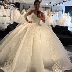 a woman in a wedding dress taking a selfie with her cell phone while looking at the camera