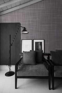 a black and white photo of a living room with two couches in front of a striped wall