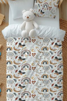 a white teddy bear sitting on top of a bed next to pillows and pillow cases