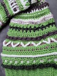 a green and white crocheted scarf laying on top of a black tablecloth