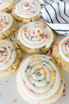 cookies with white frosting and sprinkles are on a plate next to a towel