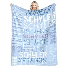 a woman holding up a blue blanket with the words schweier on it