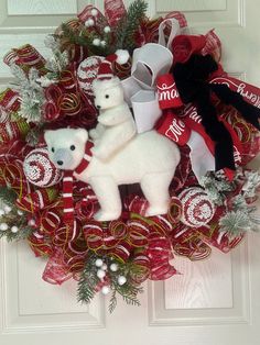 a christmas wreath with two white teddy bears and candy canes on the front door