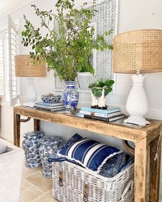 a wooden table topped with lots of blue and white pillows next to a vase filled with flowers