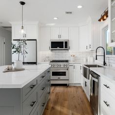 a large kitchen with white cabinets and stainless steel appliances, wood flooring and an island