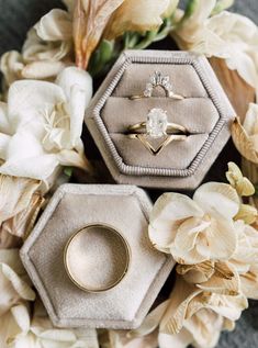 three wedding rings sitting on top of each other in front of flowers and white petals