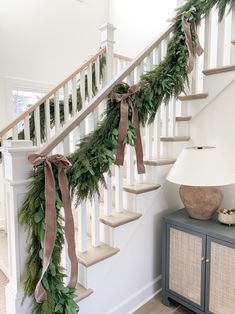 christmas garland on the banister and stairs in a home decorated with greenery for holiday