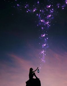 a woman sitting on top of a rock holding a lantern under a purple sky filled with stars