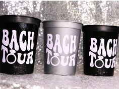 three black cups with white writing on them are sitting in front of a glitter background