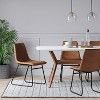 a white table with four chairs around it and a potted plant on the side