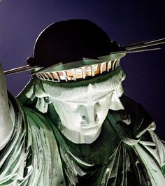 the statue of liberty is lit up at night with its head turned to the side