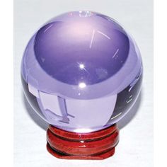 a purple glass ball sitting on top of a wooden stand next to a white wall