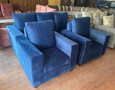 three blue chairs sitting next to each other on a hard wood floor in a store