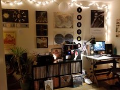 a room with lots of records on the wall and lights strung from the ceiling above it