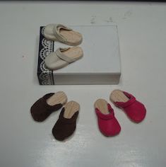 four pairs of shoes sitting on top of a white table next to a box and lace doily