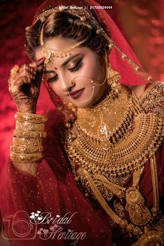 a woman in a red and gold bridal outfit, with her hands on her head