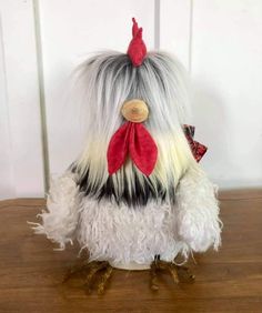 a white and black stuffed chicken sitting on top of a wooden table