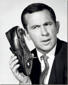 a man in a suit and tie holding up a pair of shoes