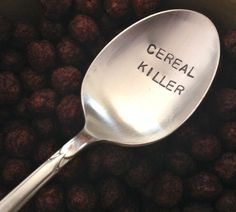 a spoon with the words cereal killer written on it in front of some chocolate balls