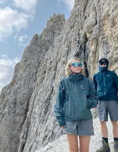 two people standing on the side of a mountain