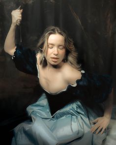 a painting of a woman in blue dress holding an object up to her ear with both hands