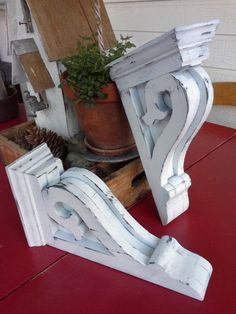 an old white wooden chair sitting on top of a red table next to a potted plant