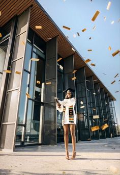 a woman standing in front of a building with lots of confetti flying around her