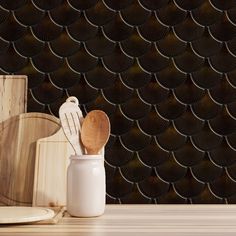 wooden utensils in a white ceramic container on a wood table against a black wall