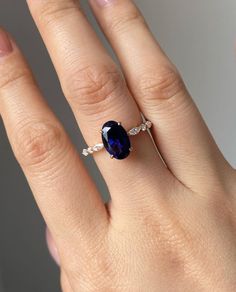 a woman's hand with a ring on it and a blue stone in the middle