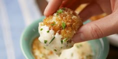 a person dipping something into a small bowl with some kind of food on it's side