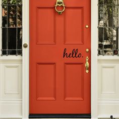 an orange front door with white trim and gold hardware on the bottom part of it