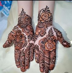 two hands that are decorated with henna and flower designs on the palm, one is showing